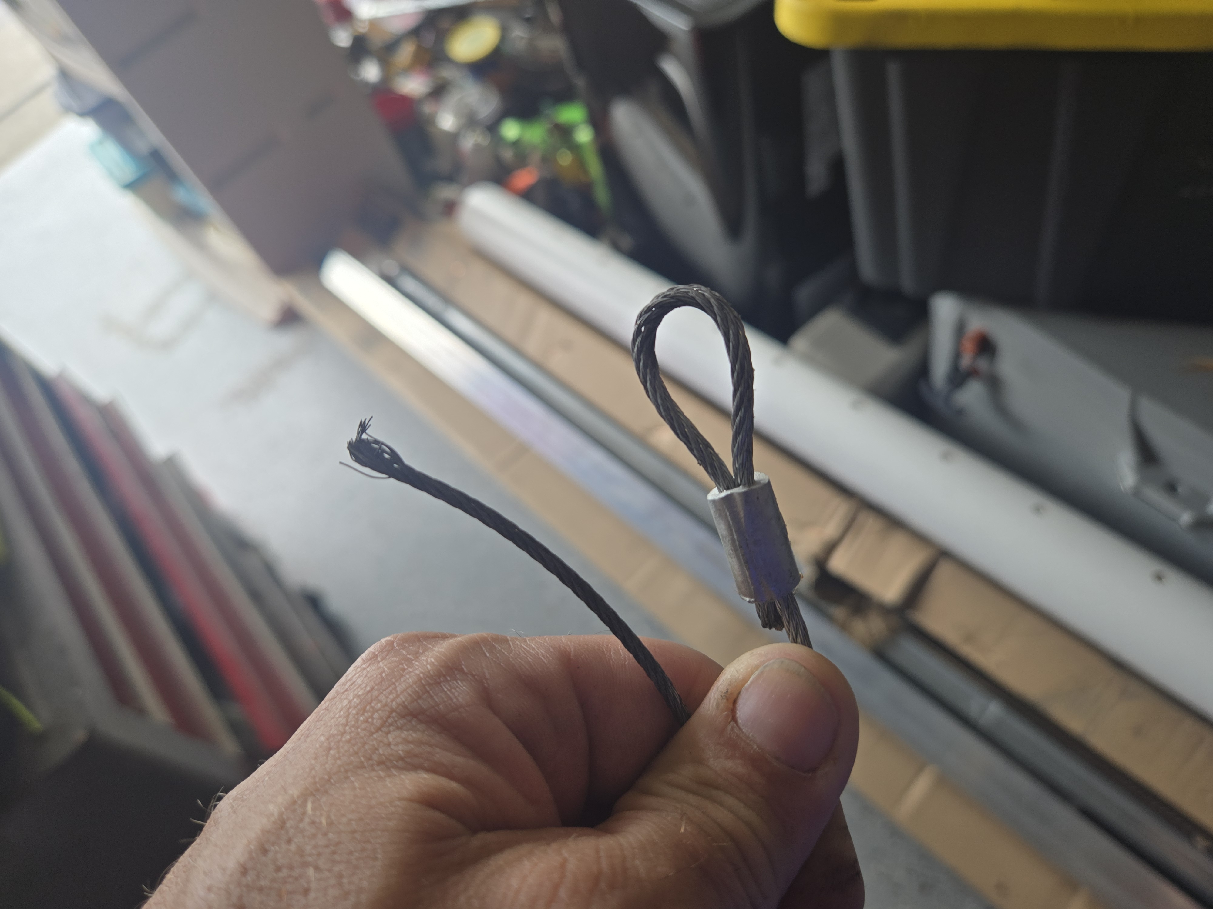 Damaged garage door cable next to a new replacement cable