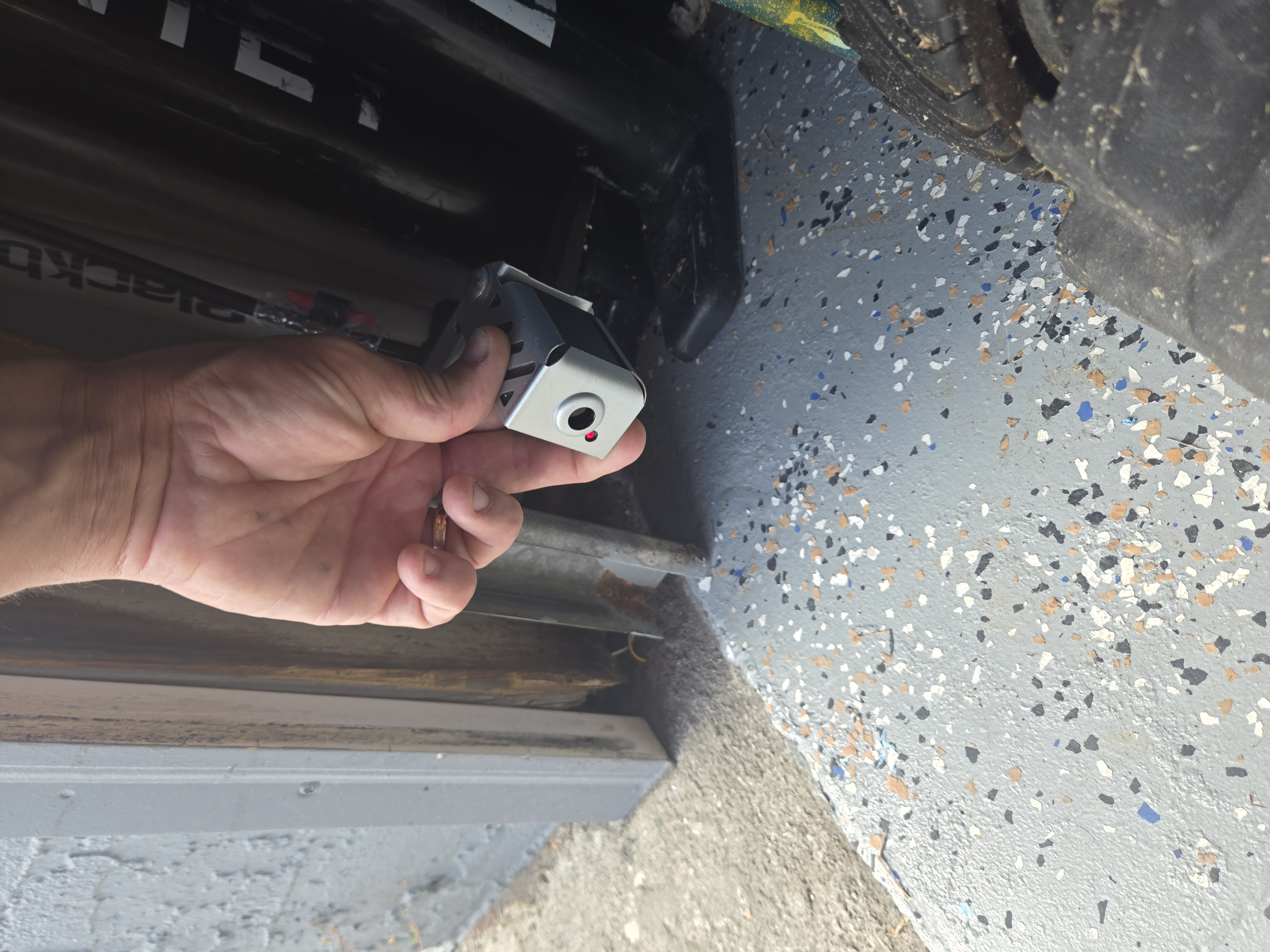 Closeup of a garage door safety sensor during inspection
