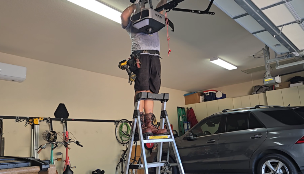 Technician performing a garage door inspection from a ladder